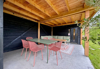 Overdekt terras met houten plafond, groene tafel en roze stoelen bij Forest villa De Bosburcht, Nederland.