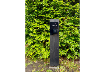 Eine Ladestation steht vor grünen Büschen an der Forest villa „De Bosburcht“ in De Kremmer, Niederlande.