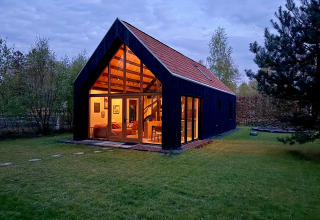 Avondfoto van Forest villa «De Bosburcht» bij De Kremmer in Nederland, warm verlicht en omgeven door bomen.