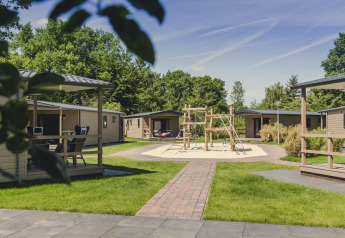 Lodge moderne Bungalette Comfort avec terrasse, aire de jeux centrale et espaces verts par beau temps.