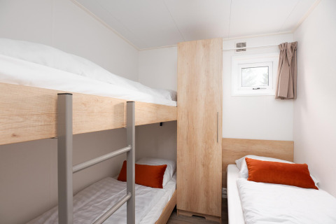 Soveværelse med køjesenge og enkeltseng, lyse vægge og skabe på Holiday park Mölke, Nederlandene.
