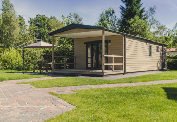 Lodge moderne avec terrasse couverte et parasol au Holiday park Mölke aux Pays-Bas, entourée de verdure.