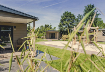 Lodge Bungalette comfort avec terrasse et aire de jeux au Holiday park Mölke, aux Pays-Bas, un jour ensoleillé.