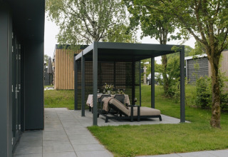 Coin salon extérieur moderne sous pergola à Oak Lodge, Holiday Park Hölte, Pays-Bas, entouré d’arbres.