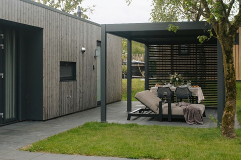 Moderne udendørs opholdsområde ved Oak Lodge i Holiday park Hölte i Holland med afslappende møbler.