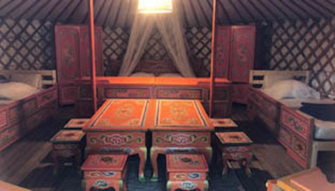 Interieur van een traditionele Mongoolse yurt met kleurrijk meubilair bij Camping Paradis Family des Issoux, Frankrijk.