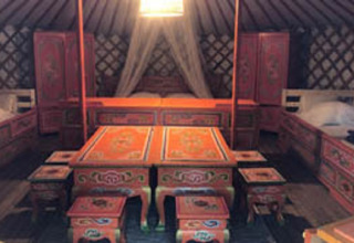Interieur van een traditionele Mongoolse yurt met kleurrijk meubilair bij Camping Paradis Family des Issoux, Frankrijk.