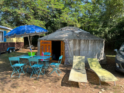 Yurt Tent op Camping Paradis Family des Issoux in Frankrijk, met blauwe stoelen en parasol buiten.