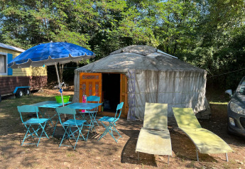 Yurt Tent op Camping Paradis Family des Issoux in Frankrijk, met blauwe stoelen en parasol buiten.
