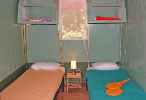 Interieur van safari tent Ecotent Lodge met twee enkele bedden en venster bij Camping Paradis Family des Issoux.