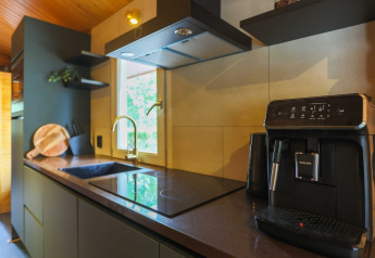Modern lodge kitchen featuring a coffee machine, induction cooktop, sink, chopping board, and window.