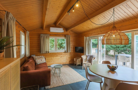 Sfeervol houten interieur in Swedish Village House bij Camping De Kleine Wereld, met zithoek en eetruimte.