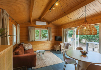 Cozy wooden interior of the Swedish Village House at Camping De Kleine Wereld, with sofa and dining area.