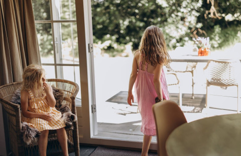 Twee meisjes in zomerkleedjes ontspannen en spelen in de Zweedse lodge bij Camping De Kleine Wereld, Nederland.