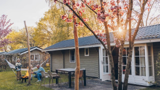 Giornata di primavera allo Swedish Country Cottage al Camping De Kleine Wereld, Olanda, con focolare e fiori.