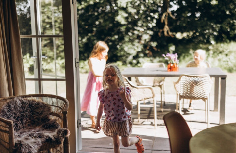 Children playing inside and outside at the Swedish Country Cottage with sofa bed at Camping De Kleine Wereld.