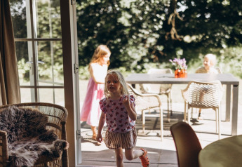 Children playing inside and outside at the Swedish Country Cottage with sofa bed at Camping De Kleine Wereld.