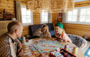 Familie spielt Monopoly in einer schwedischen Landhütte mit Sofa und Holzwänden bei Camping De Kleine Wereld.