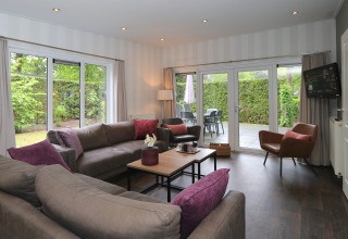 Modernes Wohnzimmer im L-Pavilion 6 bei De Achterhoek, Niederlande, mit großem Fenster und Terrassenblick.