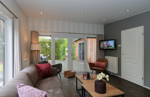 Modernes Wohnzimmer im L-Pavilion 6, De Achterhoek, Niederlande, mit Sofa, Sessel und Gartenterrasse.
