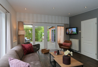 Modernes Wohnzimmer im L-Pavilion 6, De Achterhoek, Niederlande, mit Sofa, Sessel und Gartenterrasse.