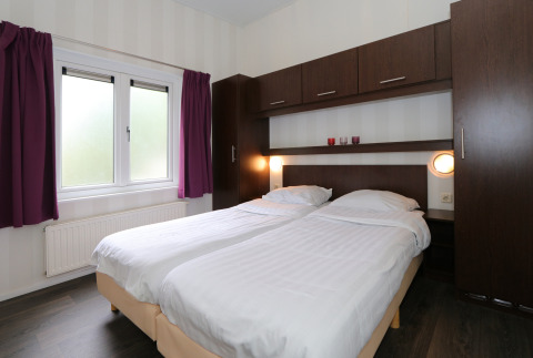 Schlafzimmer im L-Pavilion 6 in De Achterhoek, Niederlande, mit zwei Einzelbetten und Holzmöbeln.