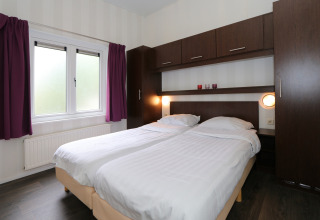 Schlafzimmer im L-Pavilion 6 in De Achterhoek, Niederlande, mit zwei Einzelbetten und Holzmöbeln.