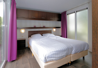 Modernes Schlafzimmer im L-Pavilion 6 in De Achterhoek, Niederlande, mit Doppelbett und lila Vorhängen.