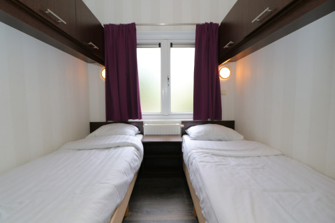 Zwei Einzelbetten mit weißer Bettwäsche in einem kompakten Zimmer im L-Pavilion 6, De Achterhoek, Niederlande.