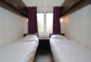 Zwei Einzelbetten mit weißer Bettwäsche in einem kompakten Zimmer im L-Pavilion 6, De Achterhoek, Niederlande.