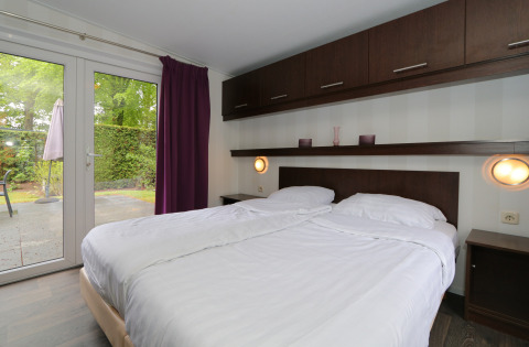 Schlafzimmer im L-Pavilion 6 in De Achterhoek, Niederlande, mit Doppelbett und Blick auf die Terrasse.