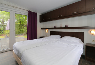 Schlafzimmer im L-Pavilion 6 in De Achterhoek, Niederlande, mit Doppelbett und Blick auf die Terrasse.