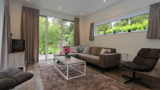 Moderne woonkamer in Pavilion 6 aan De Achterhoek, Nederland, met grote ramen met zicht op de tuin.