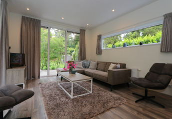 Moderne woonkamer in Pavilion 6 bij De Achterhoek, Nederland, met grote ramen en uitzicht op tuin.