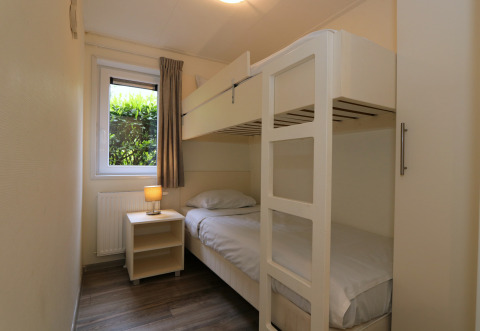 Chambre avec lits superposés, table de nuit et fenêtre sur jardin au Pavilion 6 à De Achterhoek.