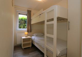 Chambre avec lits superposés, table de nuit et fenêtre sur jardin au Pavilion 6 à De Achterhoek.