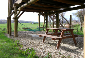 Sous une cabane dans les arbres à Treelodge, Gulperberg, Pays-Bas, avec table de pique-nique et hamac.