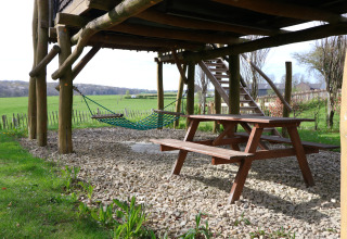 Udsigt under et træhus ved Treelodge, Gulperberg, Holland, med picnicbord og hængekøje.