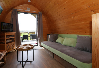 Acogedor interior de una casa en el árbol en Treelodge, Gulperberg, Países Bajos, con sofá y vista.