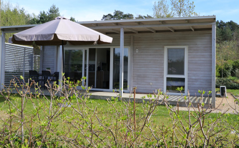 Cosy Unique-lodge met overdekt terras, tuinmeubilair, grote parasol en groene tuin omgeven door natuur.