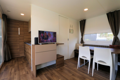 Moderne woonkamer in lodge Cosy Unique in Maasduinen, Nederland, met eettafel, tv en houten vloer.