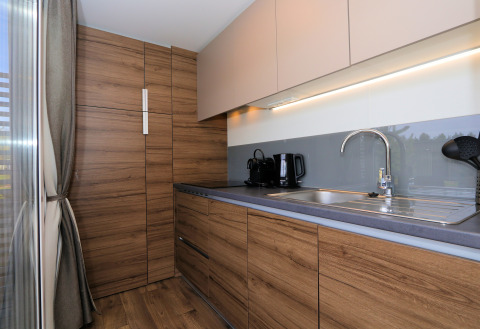 Moderne keuken met houten kasten en grijs aanrecht in lodge «Cosy Unique» in Maasduinen, Nederland.