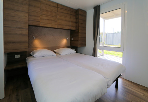 Slaapkamer in lodge 'Cosy Unique' te Maasduinen, Nederland, met twee aparte bedden en houten meubels.