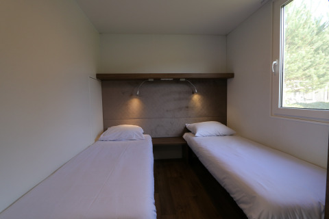 Twee eenpersoonsbedden in een lichte kamer, lodge Cosy Unique in Maasduinen, Nederland.