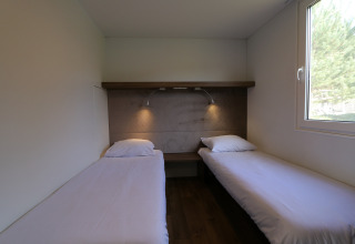 Twee eenpersoonsbedden in een lichte kamer, lodge Cosy Unique in Maasduinen, Nederland.