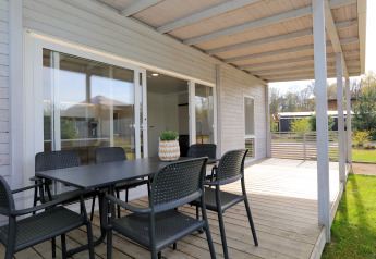 Überdachte Terrasse mit Esstisch und Stühlen bei Lodge 'Cosy Unique' in Maasduinen, Niederlande.