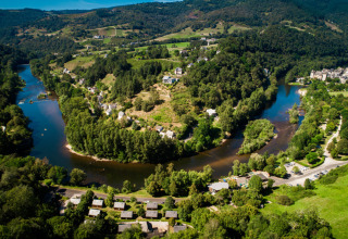Vue aérienne du camping Le Val de Saures niché au cœur des collines verdoyantes en Occitanie, France.