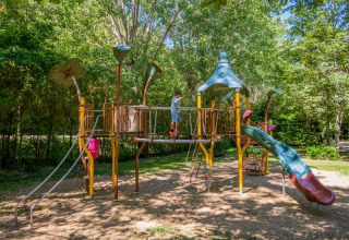 Spielplatz mit Rutsche und Klettergerüst im Grünen auf Flower Camping Le Pont du Tarn in Okzitanien, Frankreich.