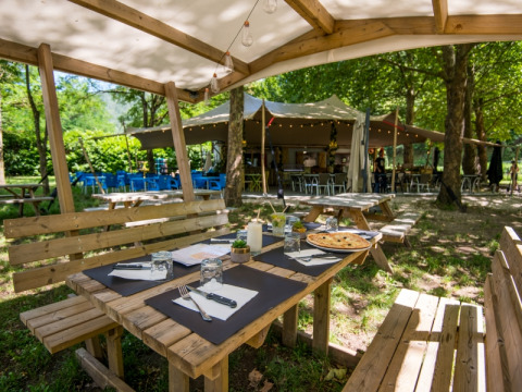 Gemütlicher Außenbereich mit Holzsitzgruppen bei Flower Camping Le Pont du Tarn in Occitanie, Frankreich.