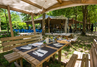 Gemütlicher Außenbereich mit Holzsitzgruppen bei Flower Camping Le Pont du Tarn in Occitanie, Frankreich.